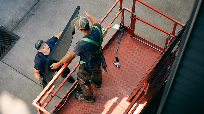 Man lifting sheet metal to another man
