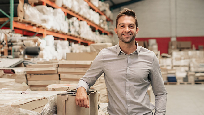 Smiling man in a warehouse.
