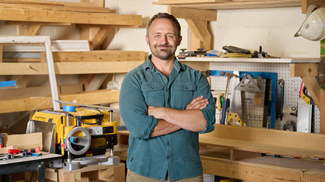 A smiling man in his workshop.