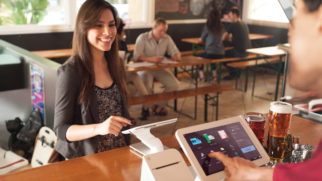 A smiling woman making a purchase at a restaurant.