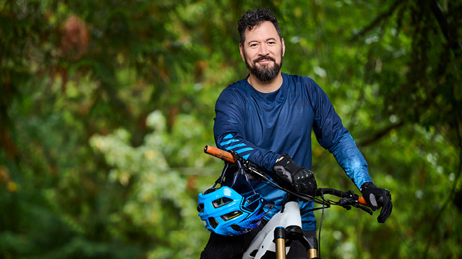a man with a beard and a blue helmet on a bicycle