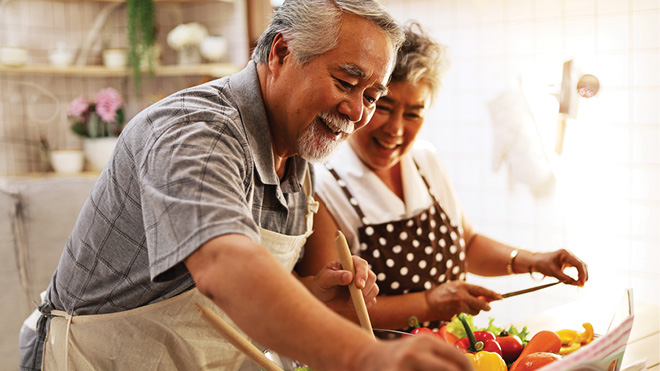Man and a woman wearing aprons and preparing food