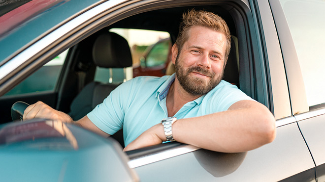 A smiling man in his vehicle.