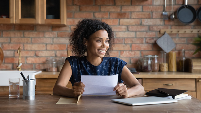 a woman smiling at a table with a piece of paper