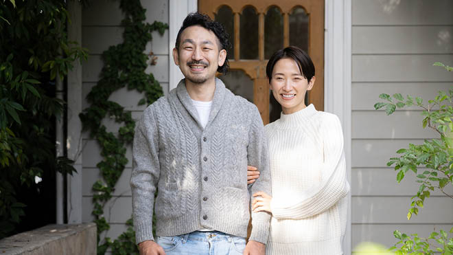 Smiling man and woman standing on the front porch of a house