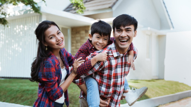 A family outside the front of their home and boy riding piggy-back on his father