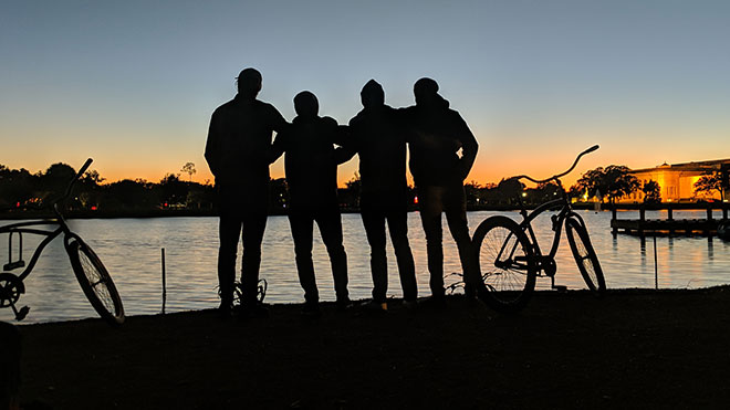 Silhouette of four people and their bikes at sunset.