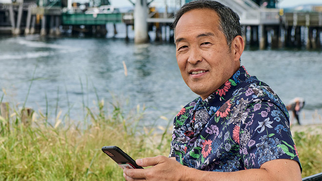 a man sitting by water holding a phone
