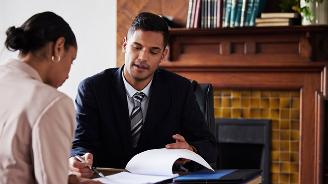 a man in a suit and tie sitting at a desk with a woman in a suit and tie