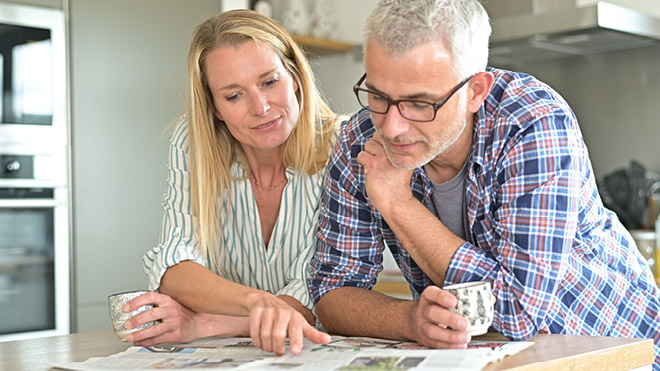 a man and woman looking at a newspaper