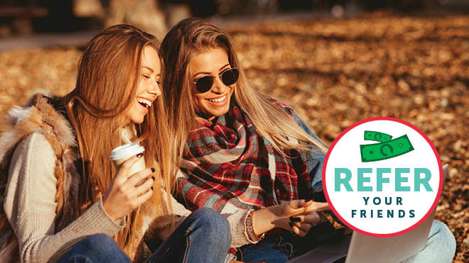 Two smiling women sitting down on leaves, badge that says "Refer Your Friends"