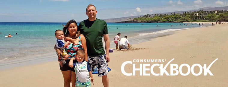Parents stand smiling with their two young children on a sunny, sandy beach with bright blue water behind them. A logo says Consumers' Checkbook on the lower right of the image.