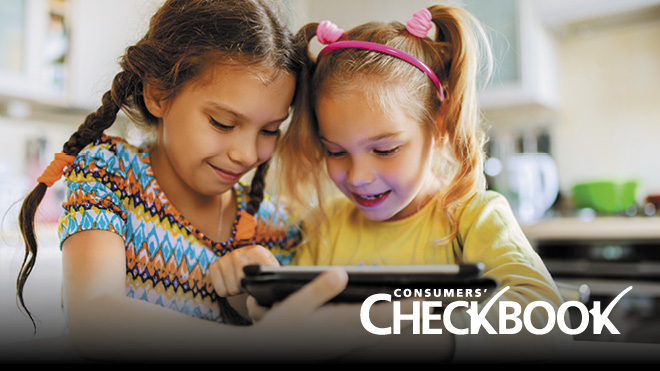 Two smiling young children, sitting side by side, looking down at a digital tablet they are holding together. Consumers' Checkbook logo in bottom right of image.