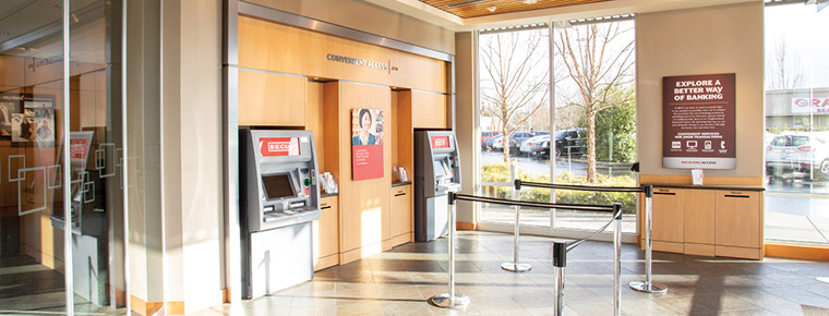  Interior view of a BECU lobby with glass windows and two ATMs positioned around the area.