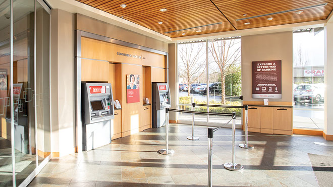 Interior view of a BECU lobby with glass windows and two ATMs positioned around the area.