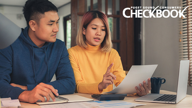 A man and woman sit together looking at a piece of paper that the woman is holding. She's talking and gesturing with one hand. The Consumers' Checkbook logo in white text is in the upper right corner of the image.