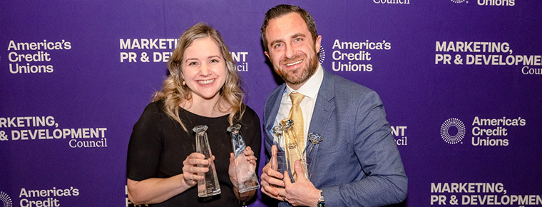 Two BECU employees holding trophies at the America’s Credit Unions Diamond Awards, standing in front of a purple branded backdrop.