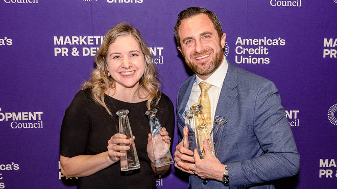 Two BECU employees holding trophies at the America’s Credit Unions Diamond Awards, standing in front of a purple branded backdrop.
