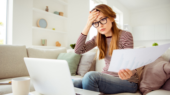 Woman with hand on forehead looking at a computer