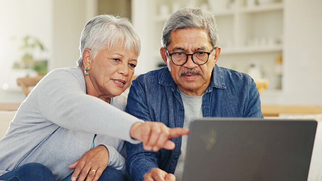 A man and woman viewing something on their laptop.