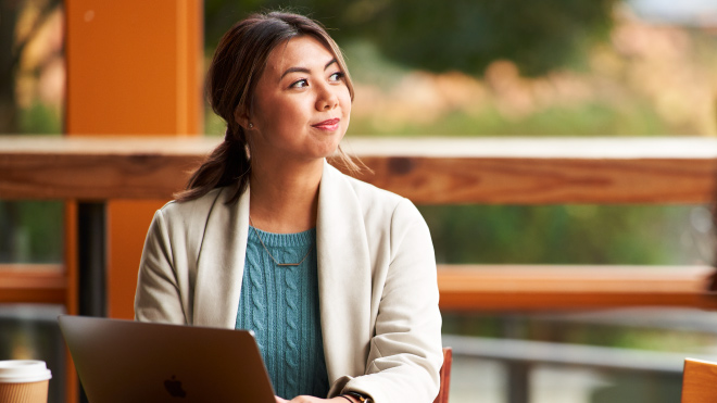 Woman wearing a blue sweater and smiling looking sideways
