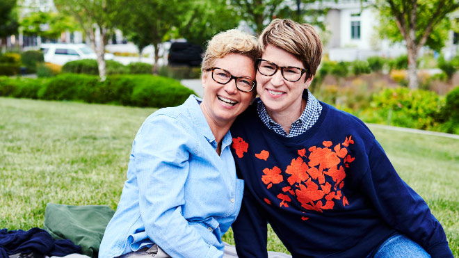 Two smiling women sitting on grass