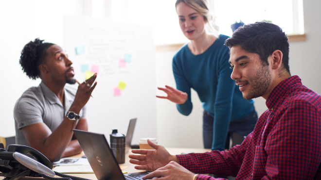 Three people having a discussion and working on a computer