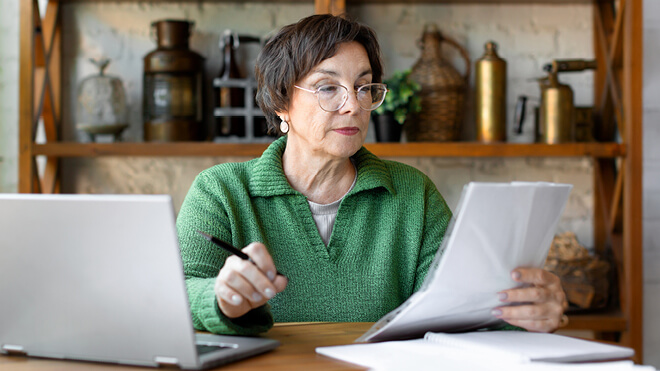 A woman wearing glasses reviewing tax documents.