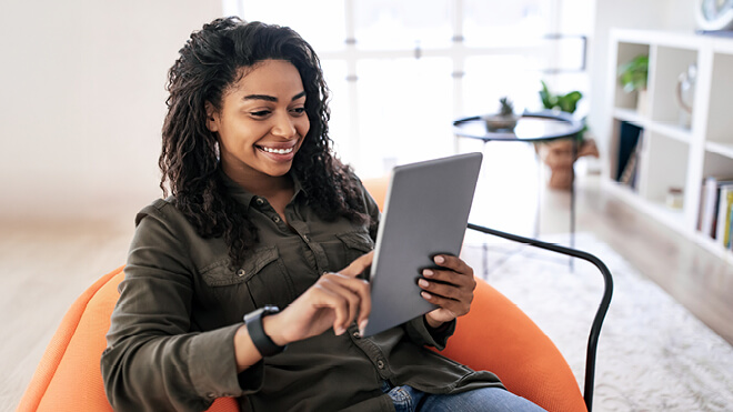A smiling woman reviewing something on her tablet.
