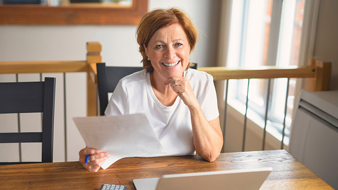 A smiling woman holding a pen and paper.