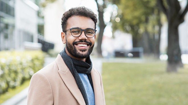 A smiling man walking outdoors.