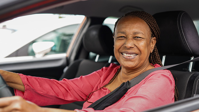 A woman happily smiling while sitting in a car