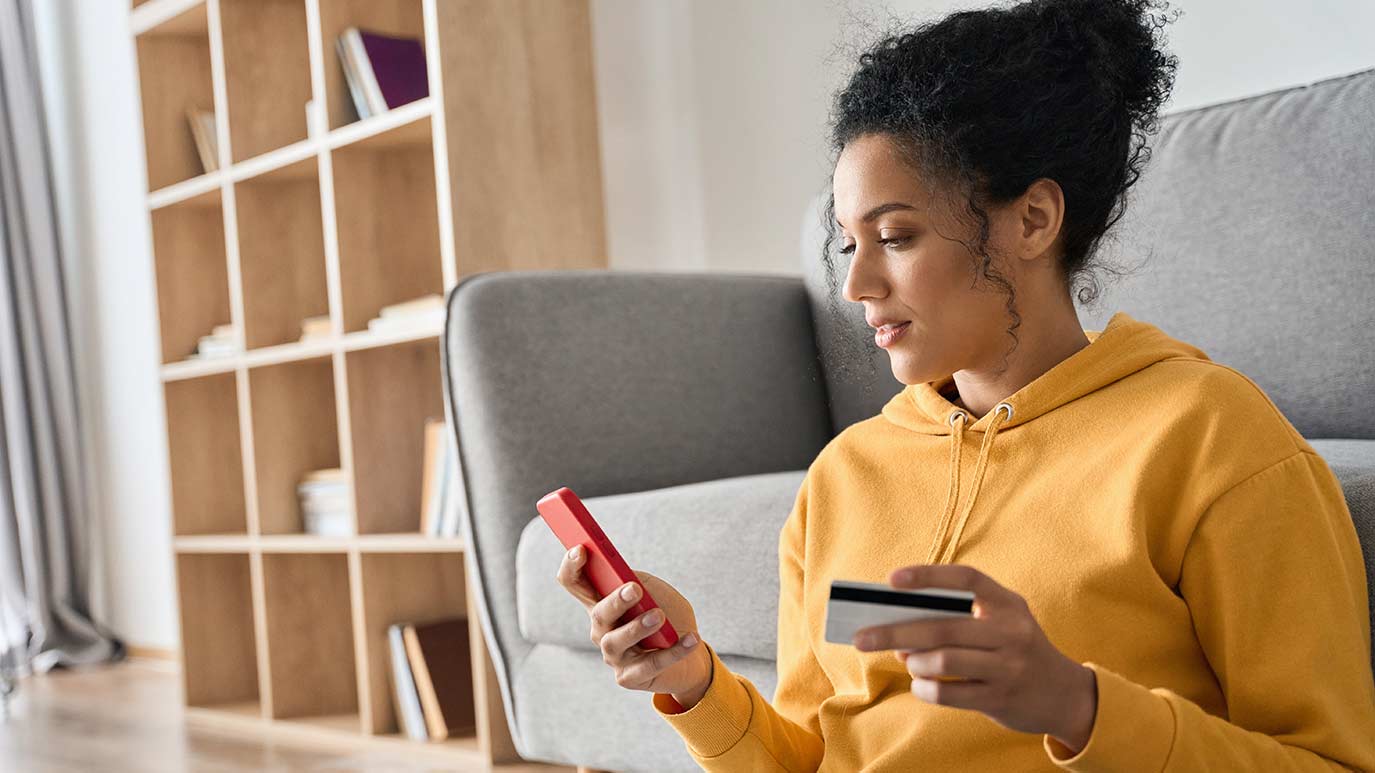 Woman holding credit card and looking at mobile phone