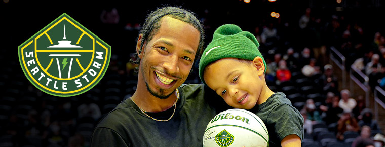 Seattle Storm basketball player holding a young child