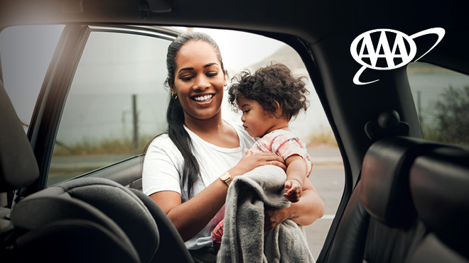 A woman putting her child in a car seat. AAA logo.