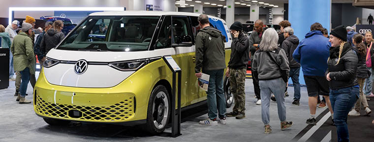 People looking at a new Volkswagen vehicle on display.