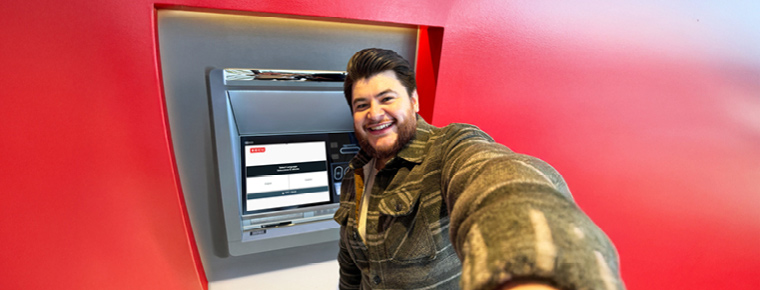 A smiling man taking a selfie by a BECU ATM.