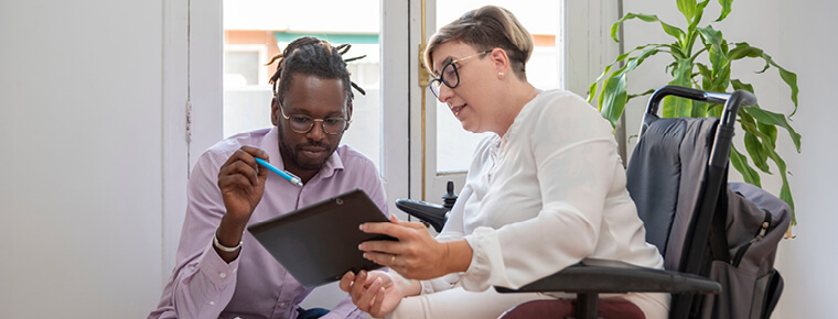 Two people looking at a tablet device screen that one of them is holding.