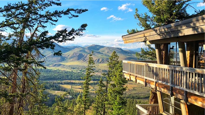 A balcony overlooking a forest and mountains.