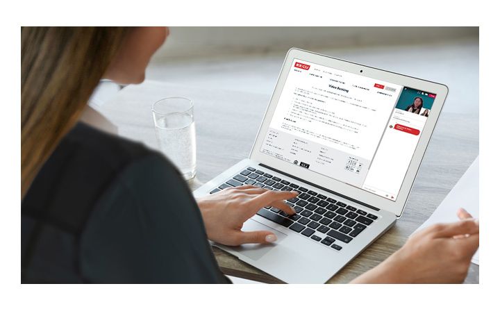 A woman is sitting down using a laptop and her back is toward the camera. She has blonde hair. As she uses her laptop, the screen is displaying BECU's Video Banking screen. 