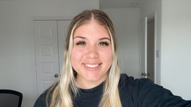 A smiling selfie headshot of BECU employee Ashlei M. She's wearing a black shirt and has blonde hair.