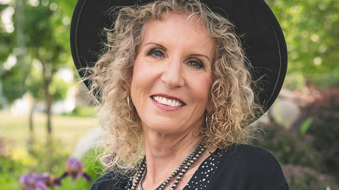 A headshot of BECU employee Paula S. She's smiling, wearing a black hat and is posing outside.