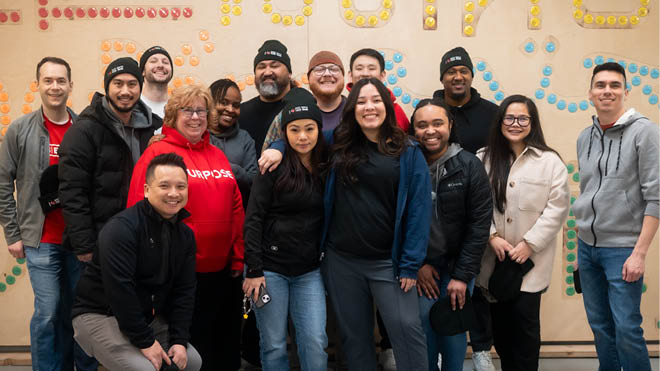 A large group of BECU employees stand in from of a colorful wall after volunteering at a local food bank.