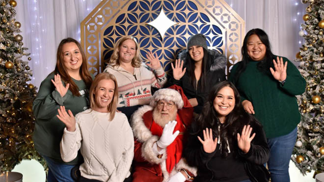 A group of BECU employees smiling as they pose with Santa Claus for a festive photo.