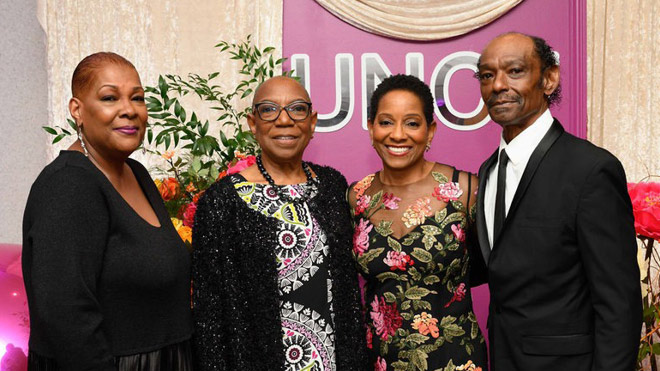 BECU President and CEO Beverly Anderson stands with members of her family at a formal indoor event, posing in front of a decorative backdrop.
