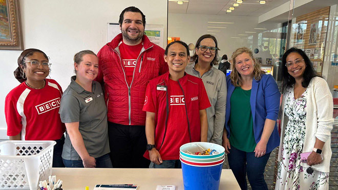 Seven BECU employees stand together, smiling at a financial health fair event.
