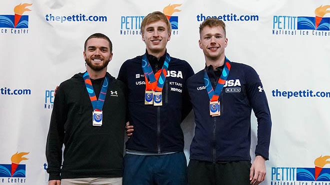 Cooper McLeod (right), alongside two teammates, on a podium wearing a medal at the Pettit Center.