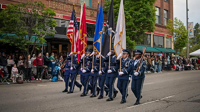 Military color guard marching with U.S. and service flags during the Spokane Armed Forces Torchlight Parade.