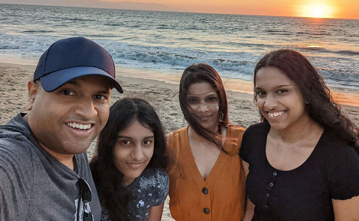 Balaji Ponnuswamy on a beach with (from left to right) his daughter Priyanka, his wife Gayathri and his daughter Varsha.