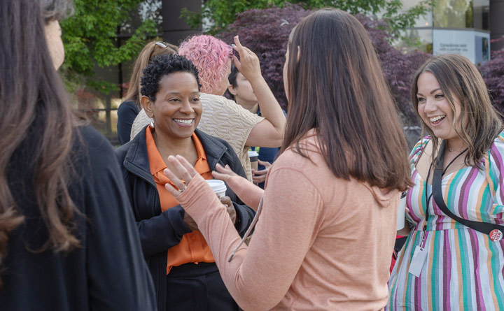 BECU CEO Beverly Anderson smiles as she engages in conversation with BECU employees outside of Tukwila Financial Center following a Pride flag raising.